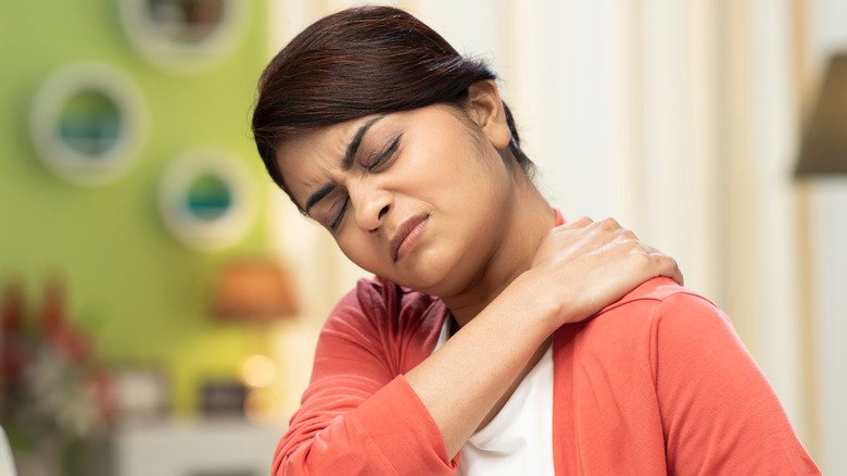 Une jeune femme se tient le cou de douleur