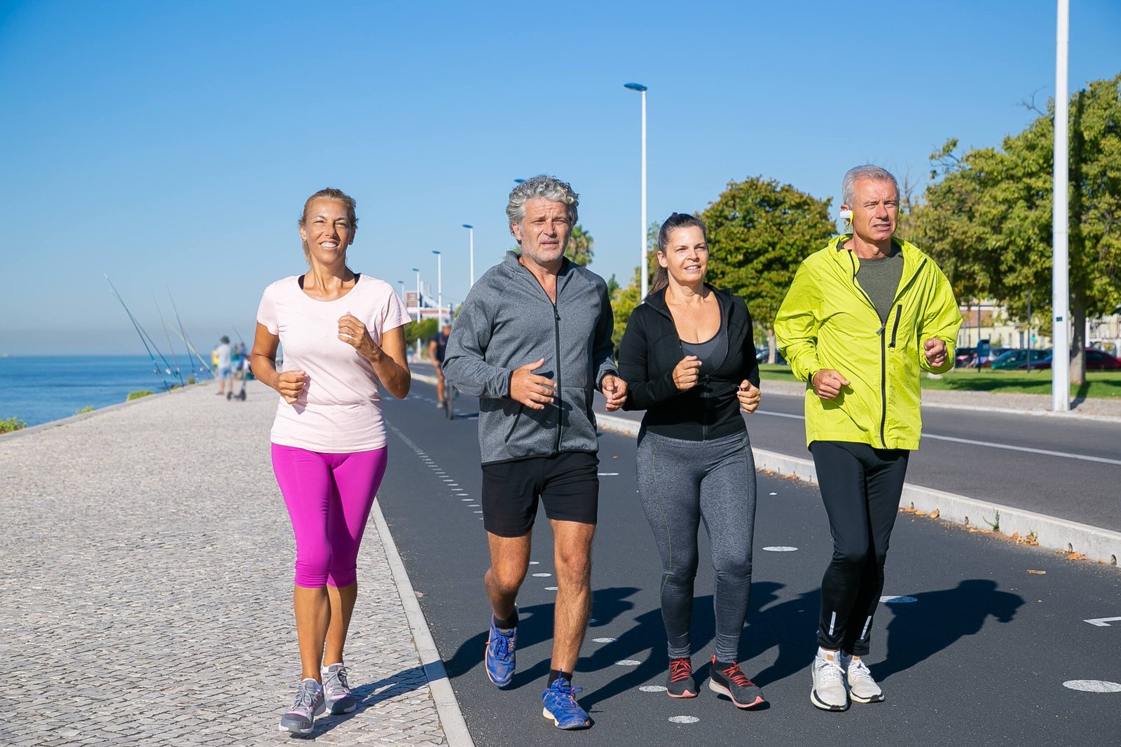 Un groupe de personnes matures en vêtements de sport, se mettant en forme en faisant du jogging le long de la rive.