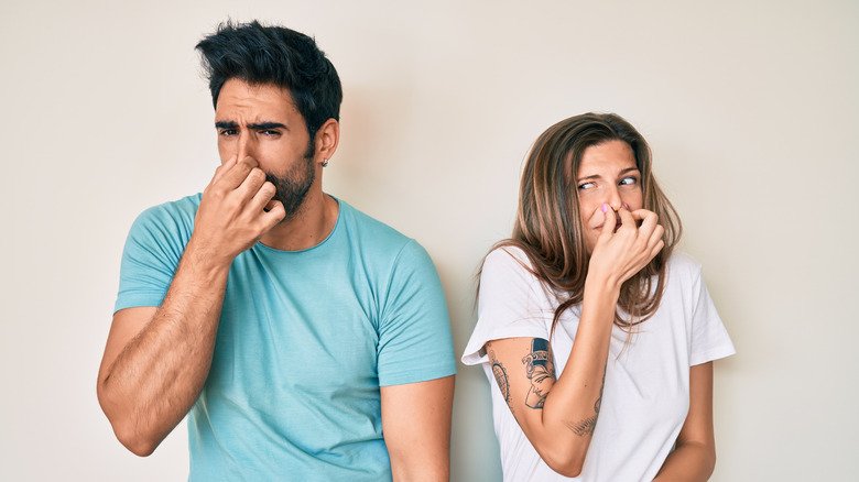 Homme et femme se tenant le nez à cause de l'odeur