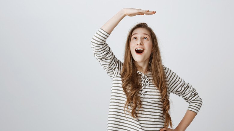 femme avec la main sur la tête indiquant la taille